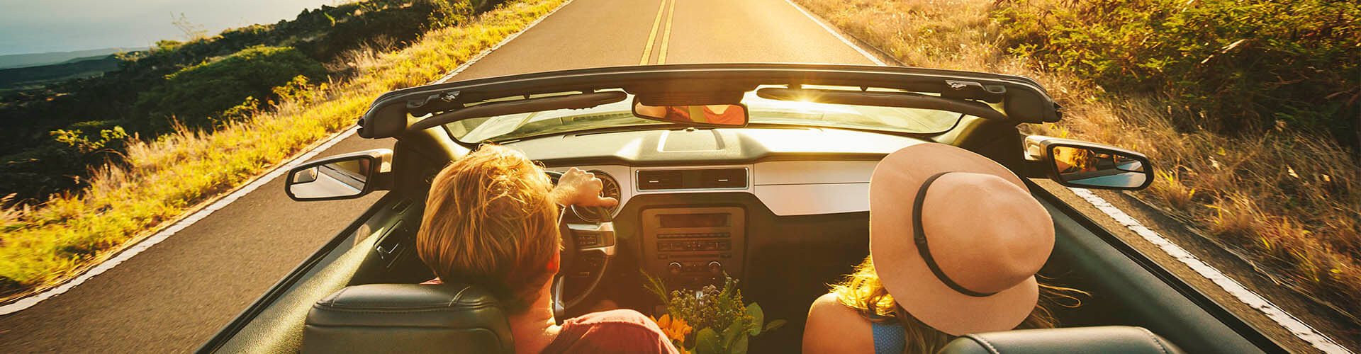 Seguro del Automóvil - Pareja feliz conduciendo por la carretera con su coche descapotable Seguro del Automóvil - Pareja feliz conduciendo por la carretera con su coche descapotable