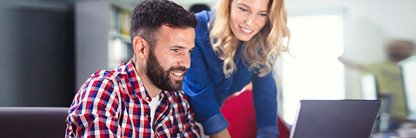 Compraventa de Divisas en Contado - Compañeros de trabajo con camisa de cuadros rojos y camisa vaquera, trabajando juntos frente a un portatil en la oficina Compraventa de Divisas en Contado - Compañeros de trabajo con camisa de cuadros rojos y camisa vaquera, trabajando juntos frente a un portatil en la oficina