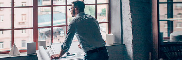 Anticipo de Exportaciones para empresas - Un hombre de negocios mirando por la ventana Anticipo de Exportaciones para empresas - Un hombre de negocios mirando por la ventana