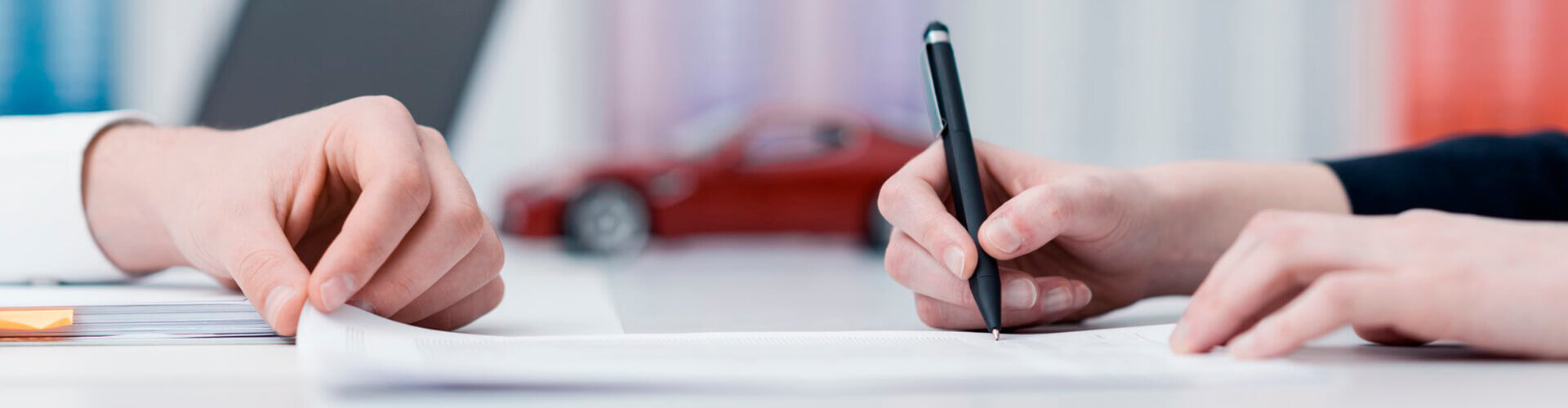 Rural Renting de Automoción y Equipamientos empresas - Manos firmando un contrato en la oficina con un coche de fondo Rural Renting de Automoción y Equipamientos empresas - Manos firmando un contrato en la oficina con un coche de fondo