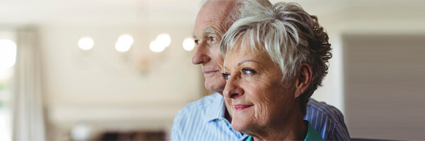 Seguros de Rentas - Pareja senior sonriendo en el salon de su casa Seguros de Rentas - Pareja senior sonriendo en el salon de su casa