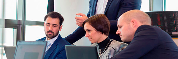 Transferencias y ordenes de pago para empresas - Varias personas trajeadas reunidas, mirando los portátiles en la oficina Transferencias y ordenes de pago para empresas - Varias personas trajeadas reunidas, mirando los portátiles en la oficina
