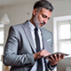 Momento Digitalizar mis gestiones- Hombre de mediana edad con barba, traje gris y corbata negra trabajado en la oficina con una tablet pensando en digitalizar las gestiones de su empresa Momento Digitalizar mis gestiones- Hombre de mediana edad con barba, traje gris y corbata negra trabajado en la oficina con una tablet pensando en digitalizar las gestiones de su empresa