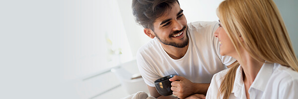 Seguros de Ahorro - Pareja joven feliz y enamorados en pijama, utilizando la tablet tumbados en el sofa de casa buscando seguros de ahorro Seguros de Ahorro - Pareja joven feliz y enamorados en pijama, utilizando la tablet tumbados en el sofa de casa buscando seguros de ahorro