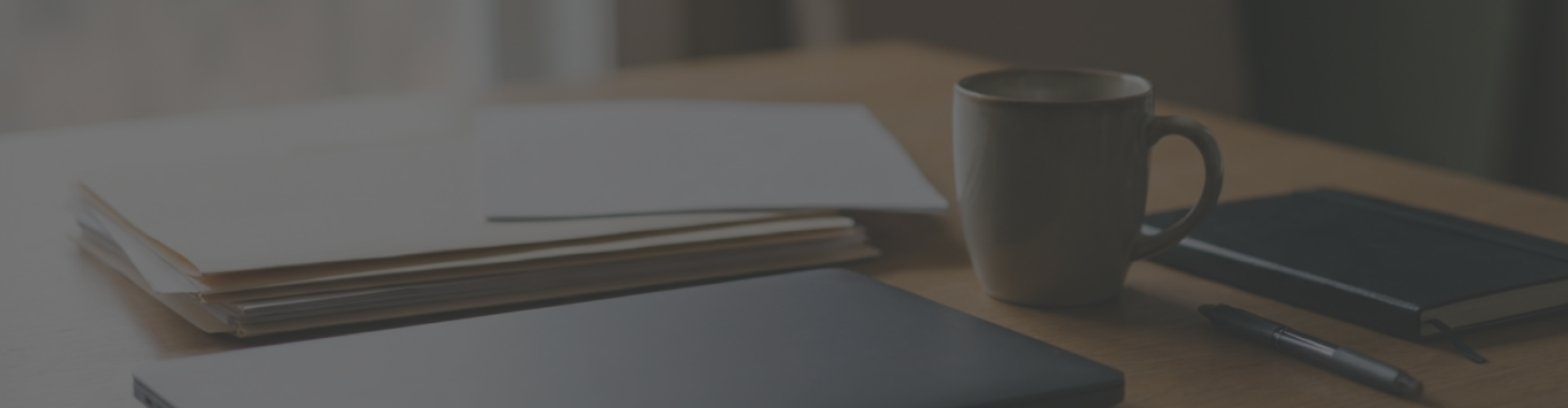 mesa de trabajo con folios en blanco y una taza