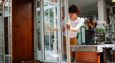 Mujer abriendo la ventana de su cafetería
