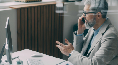 Hombre trajeado frente al ordenador hablando por teléfono