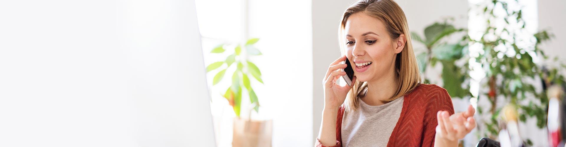 Líneas de inversión - Una mujer está hablando por teléfono en su oficina frente a su portátil