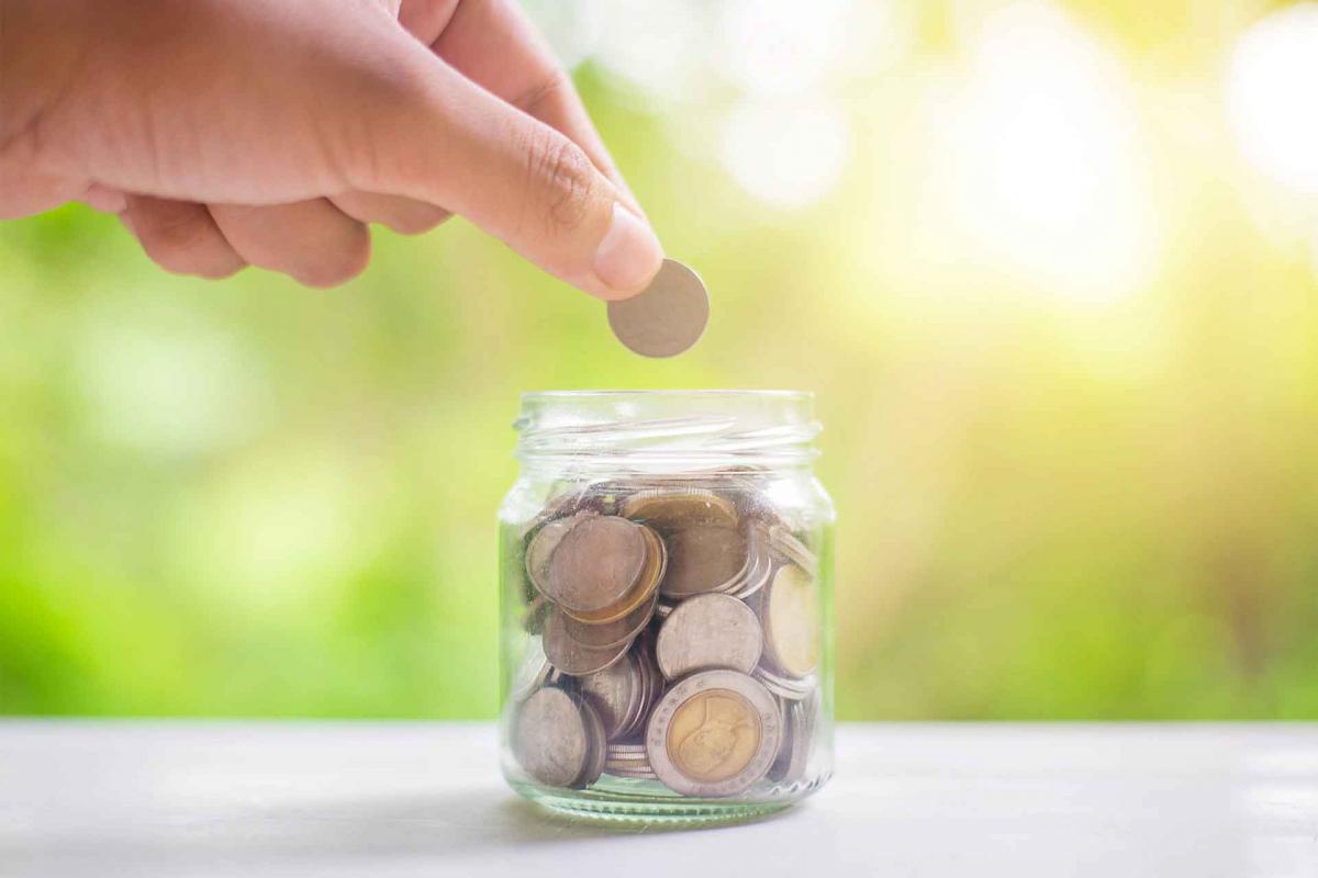 Mano metiendo monedas a un tarro Mano metiendo monedas a un tarro