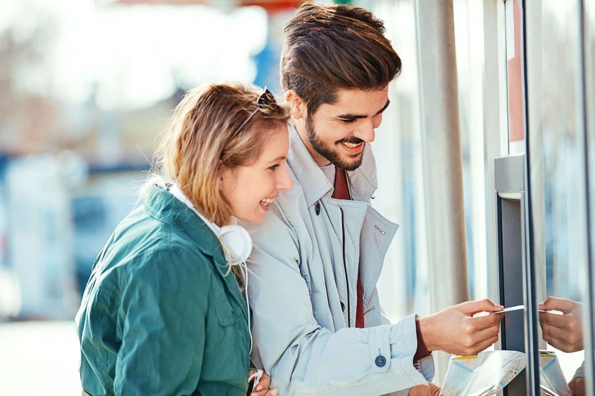 Dos personas contentas sacando dinero del cajero Dos personas contentas sacando dinero del cajero