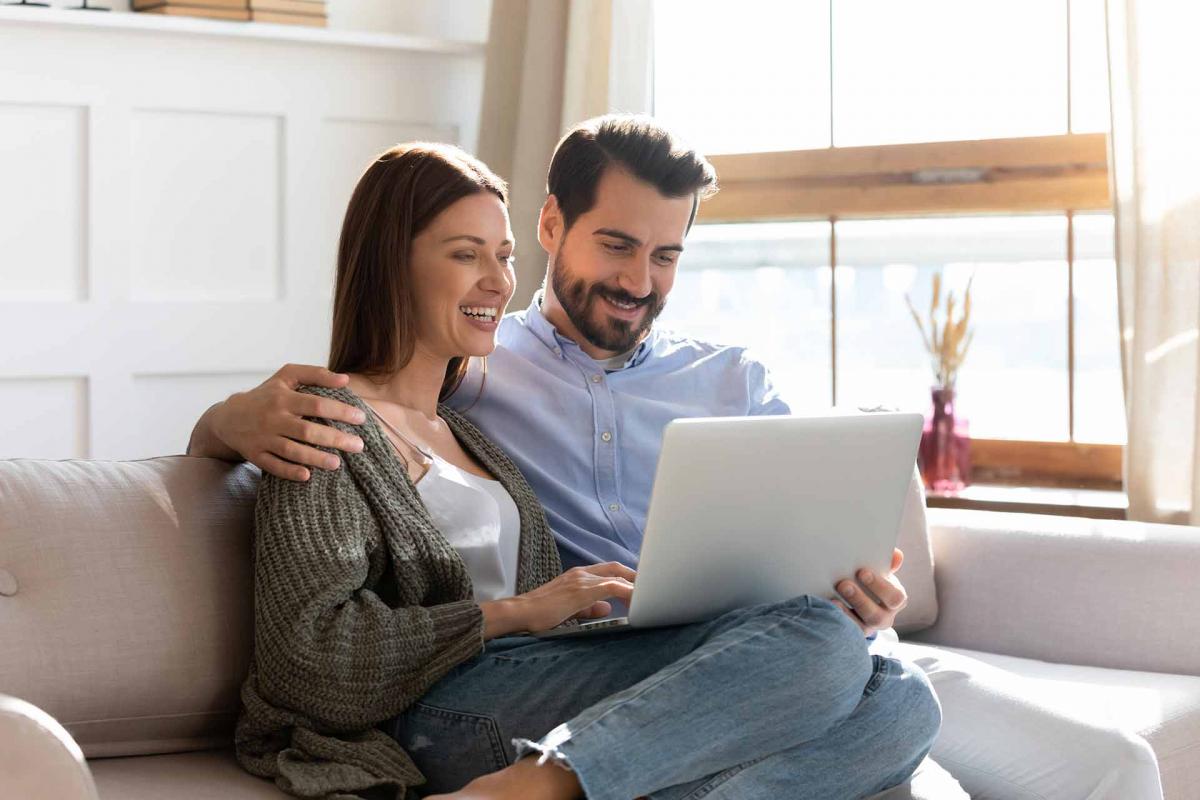 Pareja mirando al ordenador en el sofa Pareja mirando al ordenador en el sofa