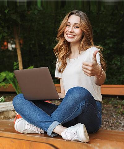 Momento Comenzar a vender por Internet - Joven chica sonriendo sentada utilizando un portatil