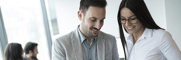 Asesoramiento Financiero - Compañeros de trabajo trabajando juntos en la oficina sonriendo y con una tablet en la mano Asesoramiento Financiero - Compañeros de trabajo trabajando juntos en la oficina sonriendo y con una tablet en la mano