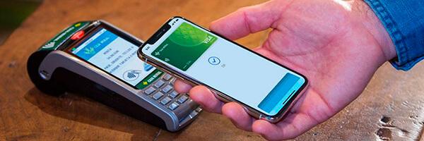 Apple Pay - Persona pagando con apple pay en su movil en el tpv de un comercio Apple Pay - Persona pagando con apple pay en su movil en el tpv de un comercio
